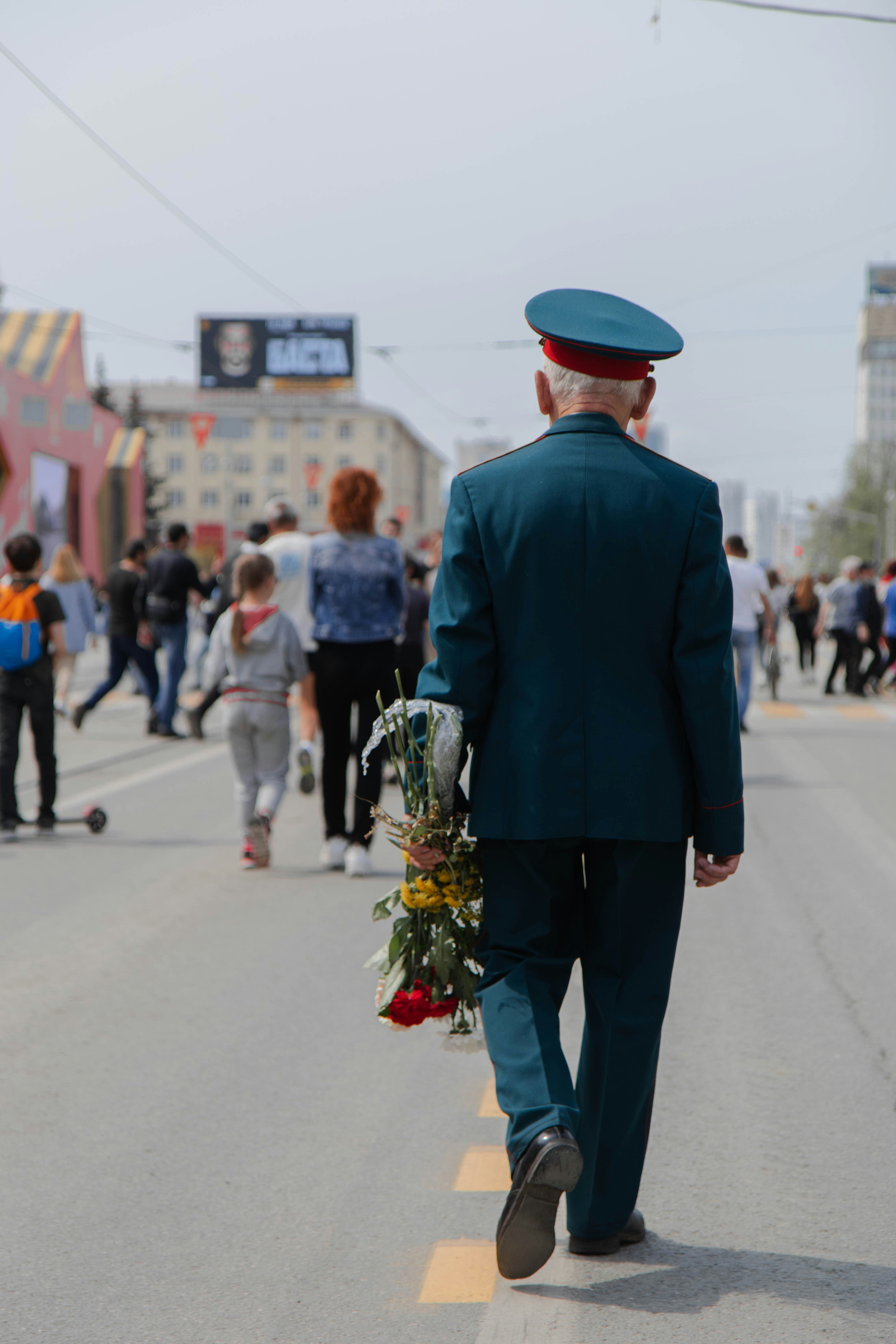 Veteran walking with flowers in hand as part of citizen parade.